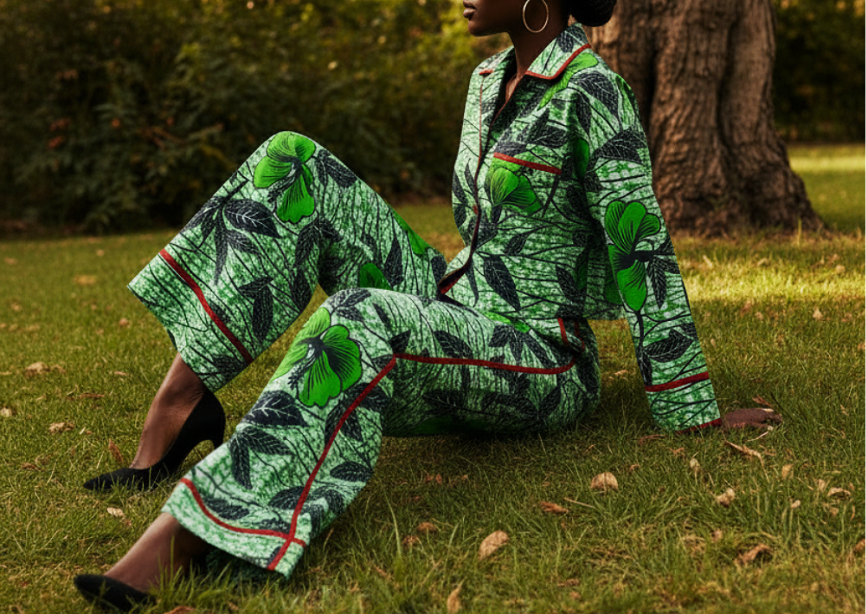 A young model wearing a floral green outfit by Maison Aria, sitting on a lawn