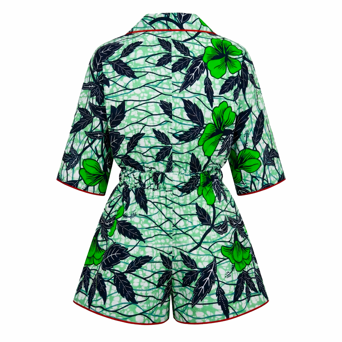 A women's short-sleeve romper shown from the back, featuring a green and black tropical floral print with a red piping trim.