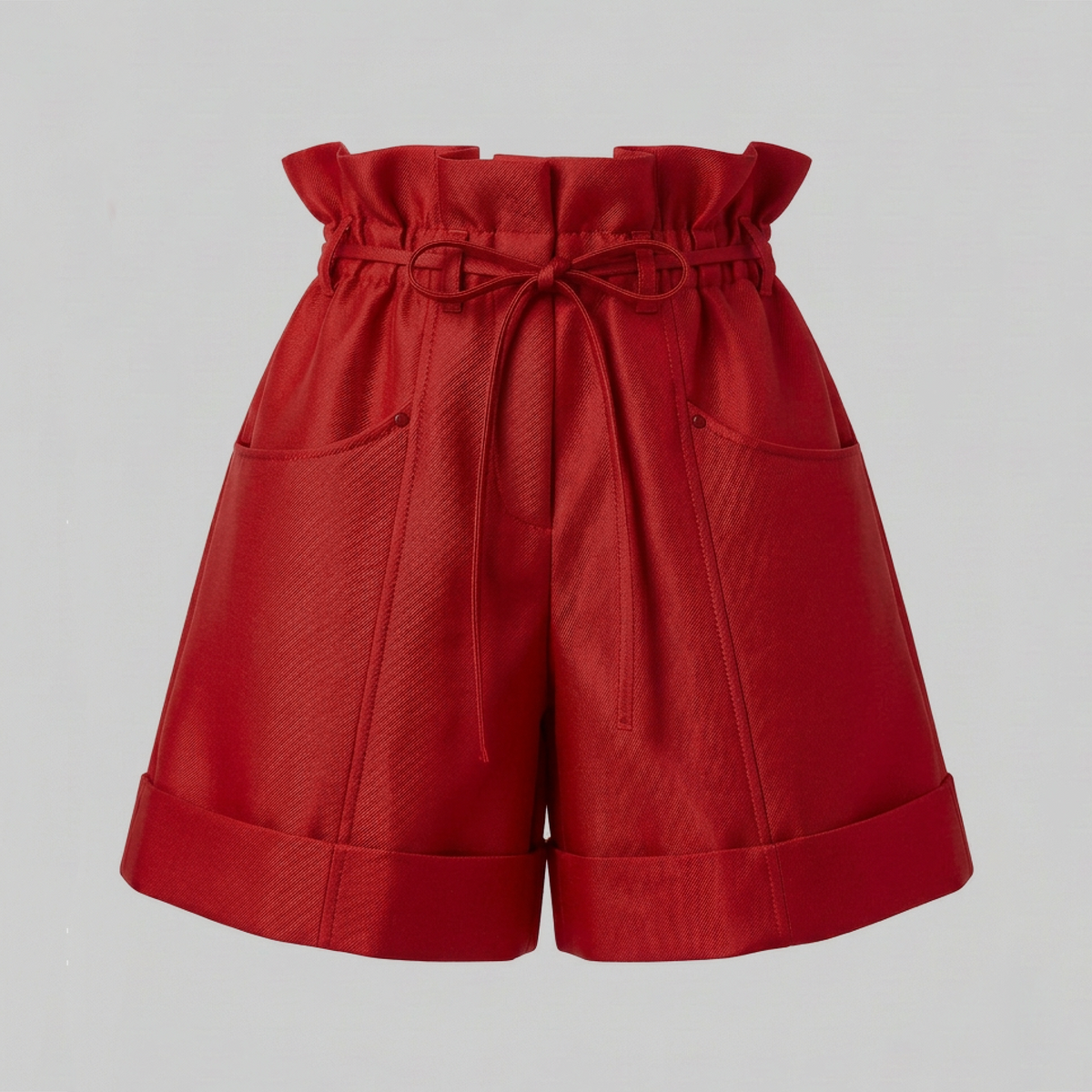 Red high-waisted shorts with a paperbag waist, drawstring tie, and side pockets, shown against a plain light gray background.
