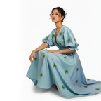 Woman wearing a light blue dress with green patterns on a white background