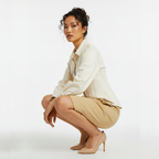 Woman in a white shirt and beige skirt posing on a white background