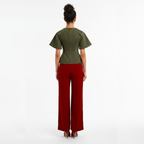 Woman wearing a green top and red pants on a white background