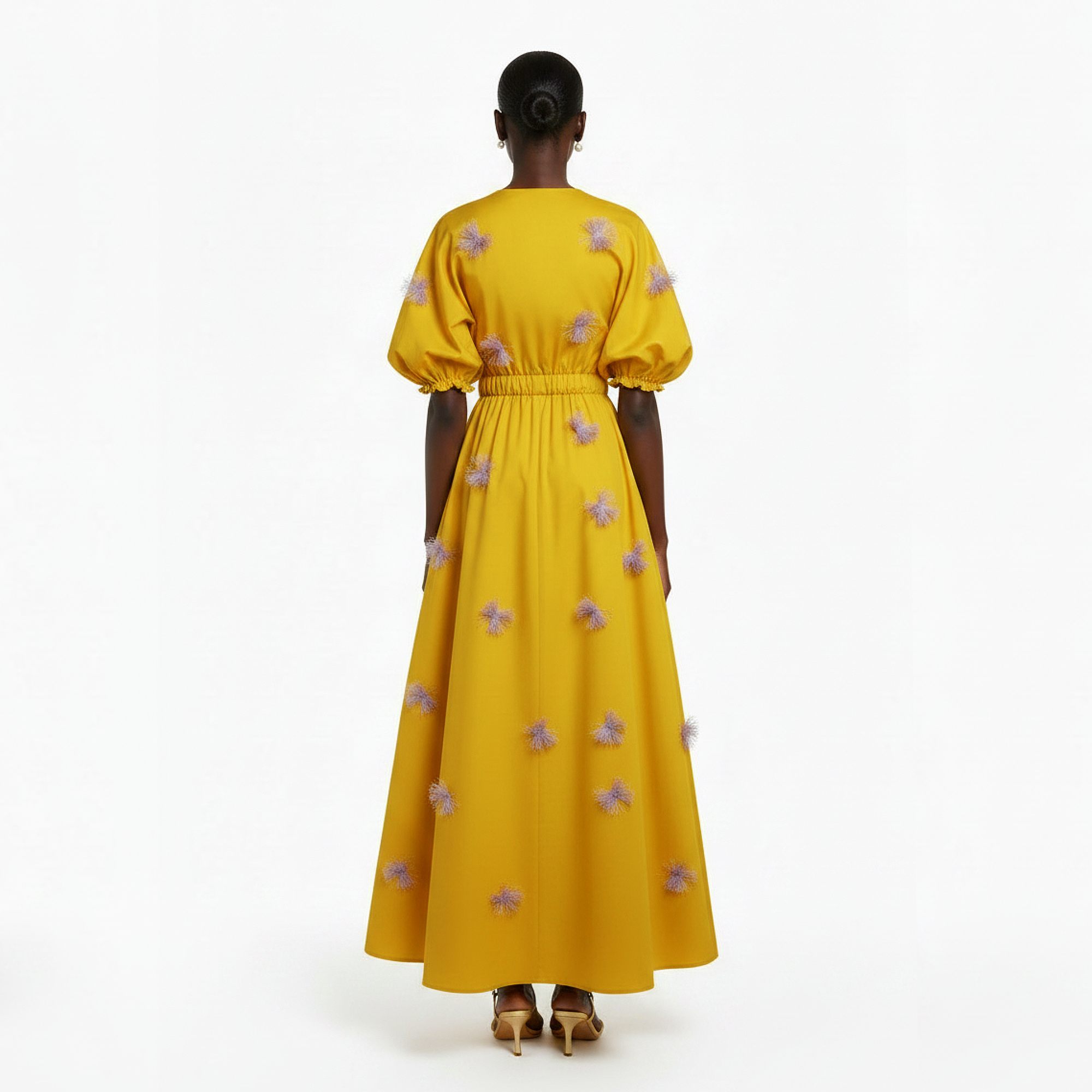 Woman wearing a yellow dress with floral patterns on a white background