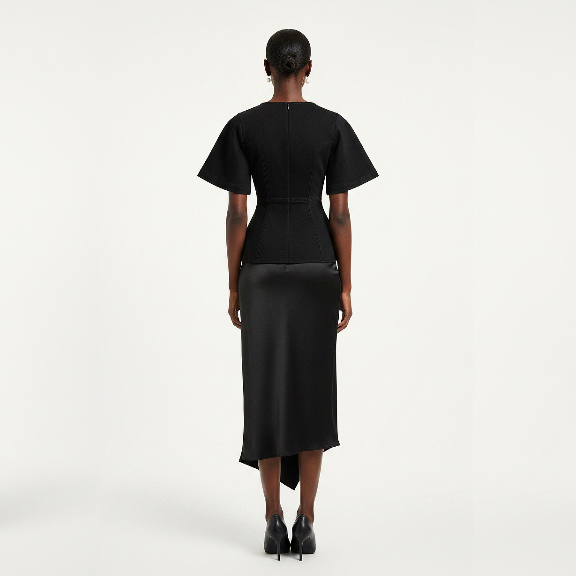 Person wearing a black dress with a belt on a white background