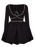 Black dress with lace detailing and pearl embellishments on a white background