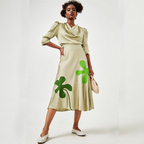 Woman wearing a beige dress with green clover patterns on a white background