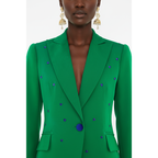 Green blazer with blue embellishments worn by a model on a white background