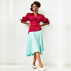 Woman wearing a dress with a red blouse and light blue skirt against a white background