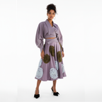 Woman wearing a lavender dress with floral embellishments on a white background