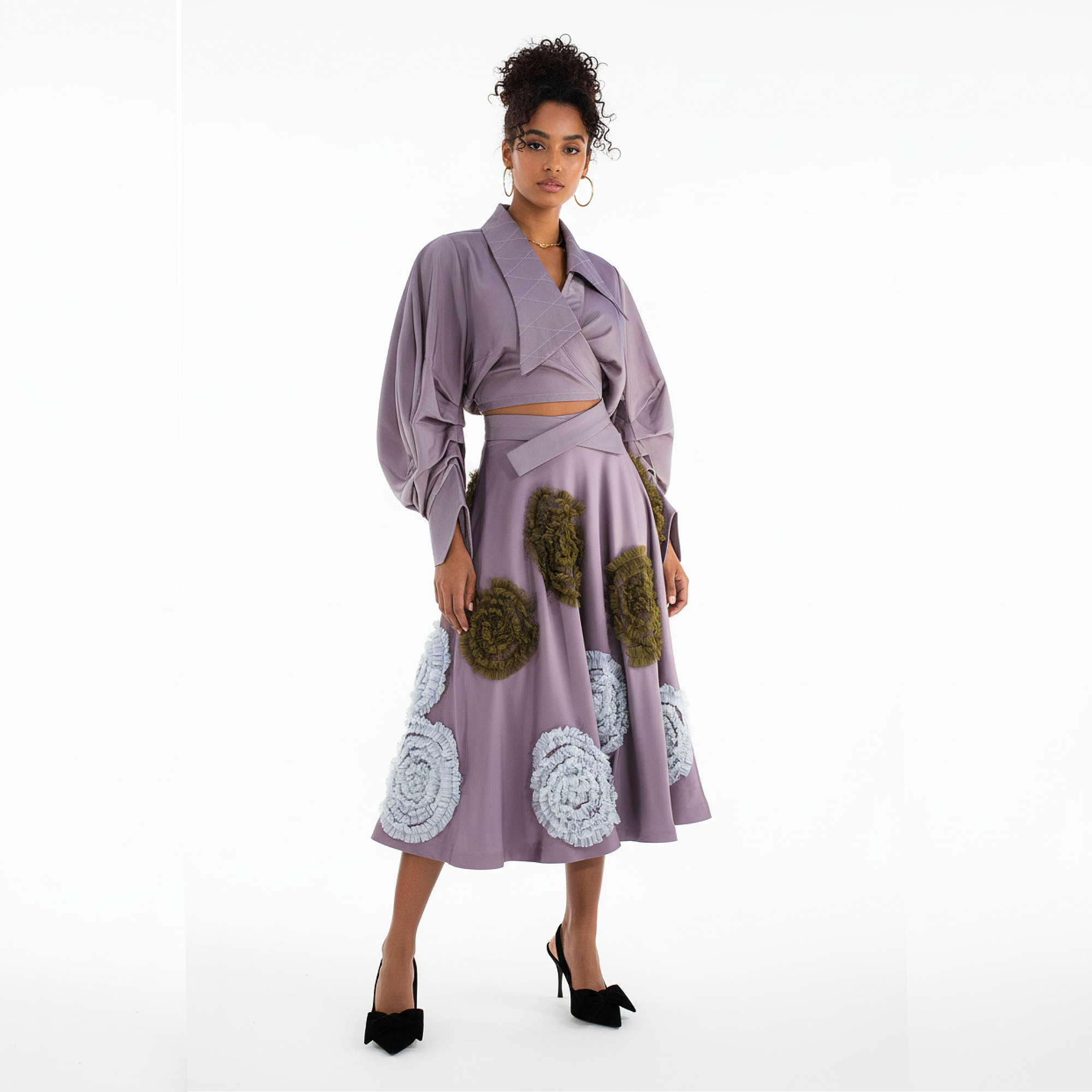 Woman wearing a lavender dress with floral embellishments on a white background