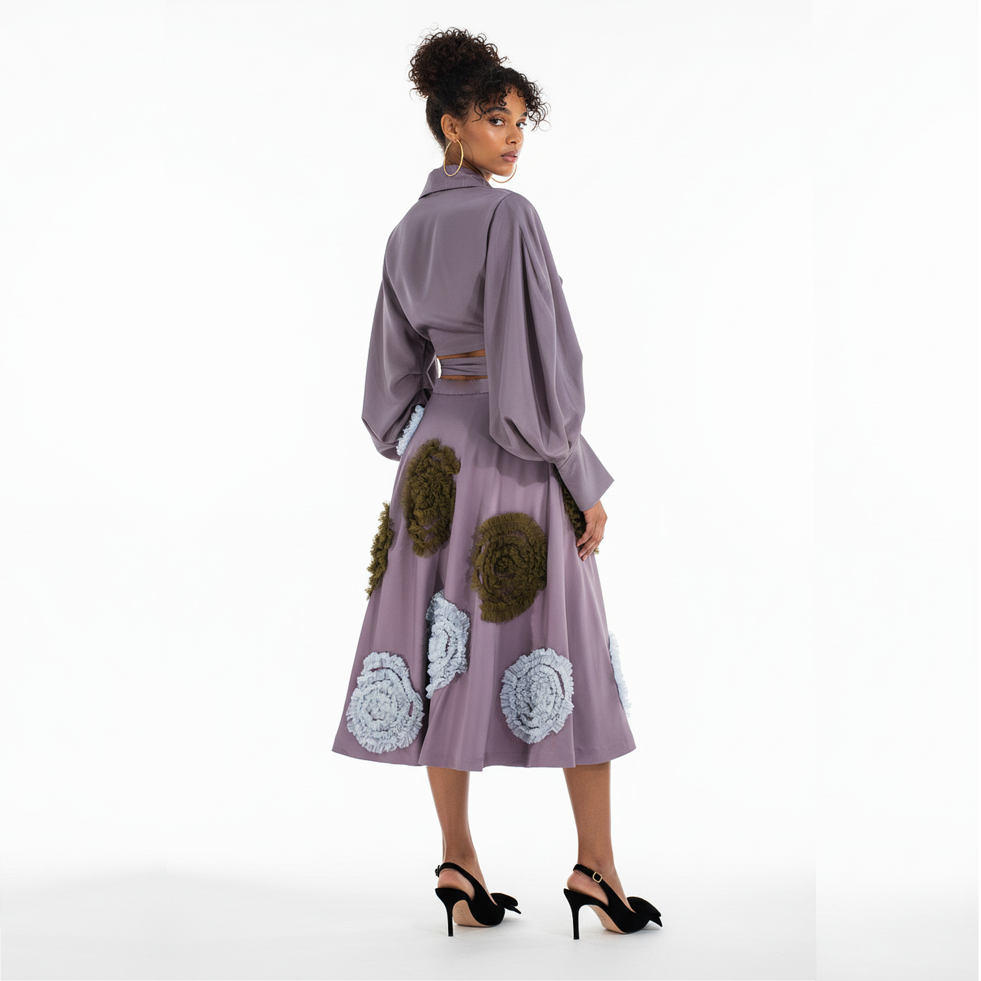 Woman wearing a purple dress with floral and geometric patterns on a white background