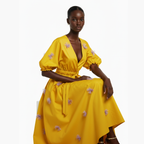 Woman wearing a yellow dress with floral embellishments on a white background