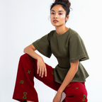 Woman wearing an olive green top and red pants with green patterns on a white background
