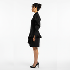 Woman wearing a black outfit with ruffled details on a white background