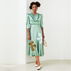 Woman wearing a green dress with floral designs against a white background