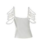 A person wearing a white top with pearl shoulder straps on a white background