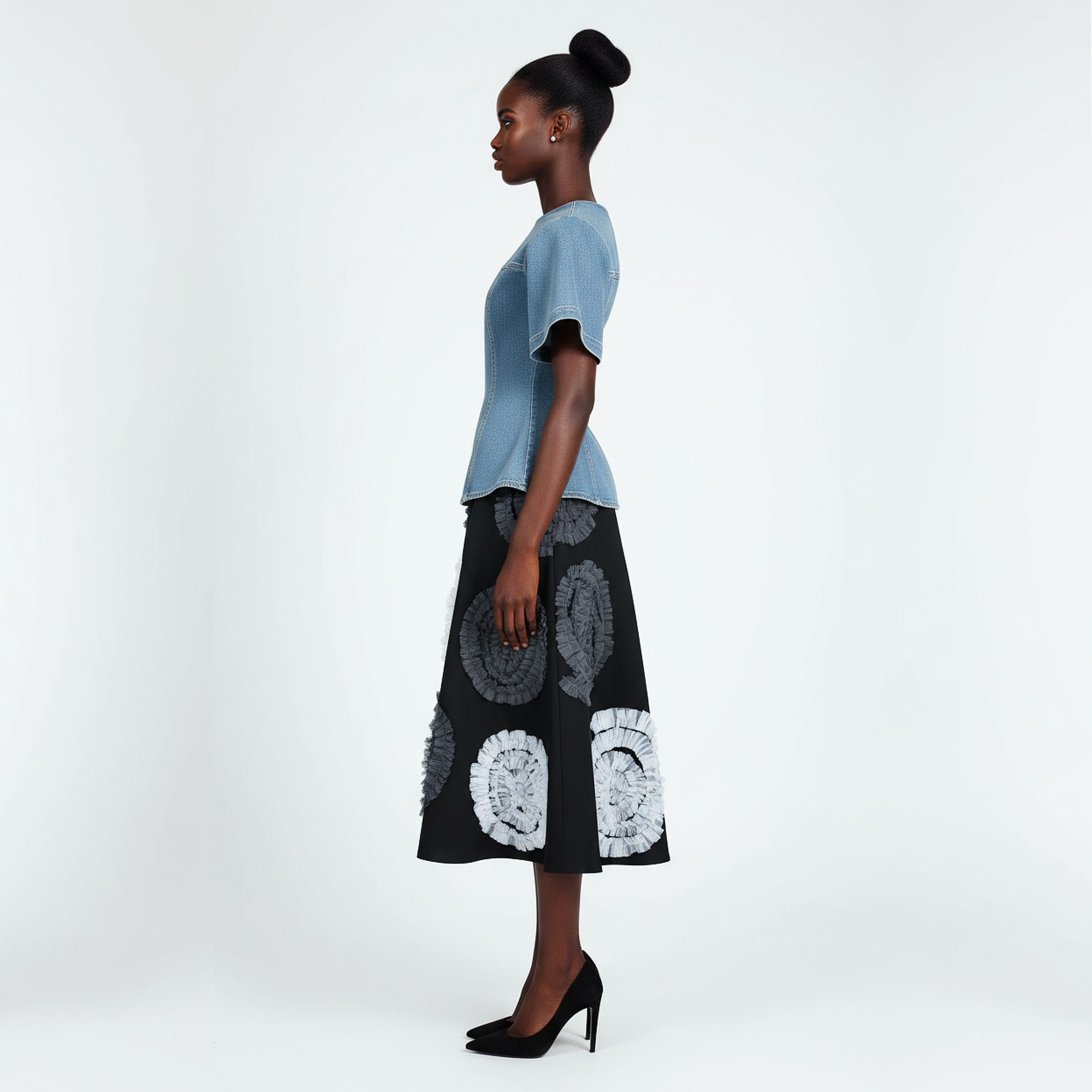 Woman wearing a light blue top and black skirt with white floral patterns on a white background