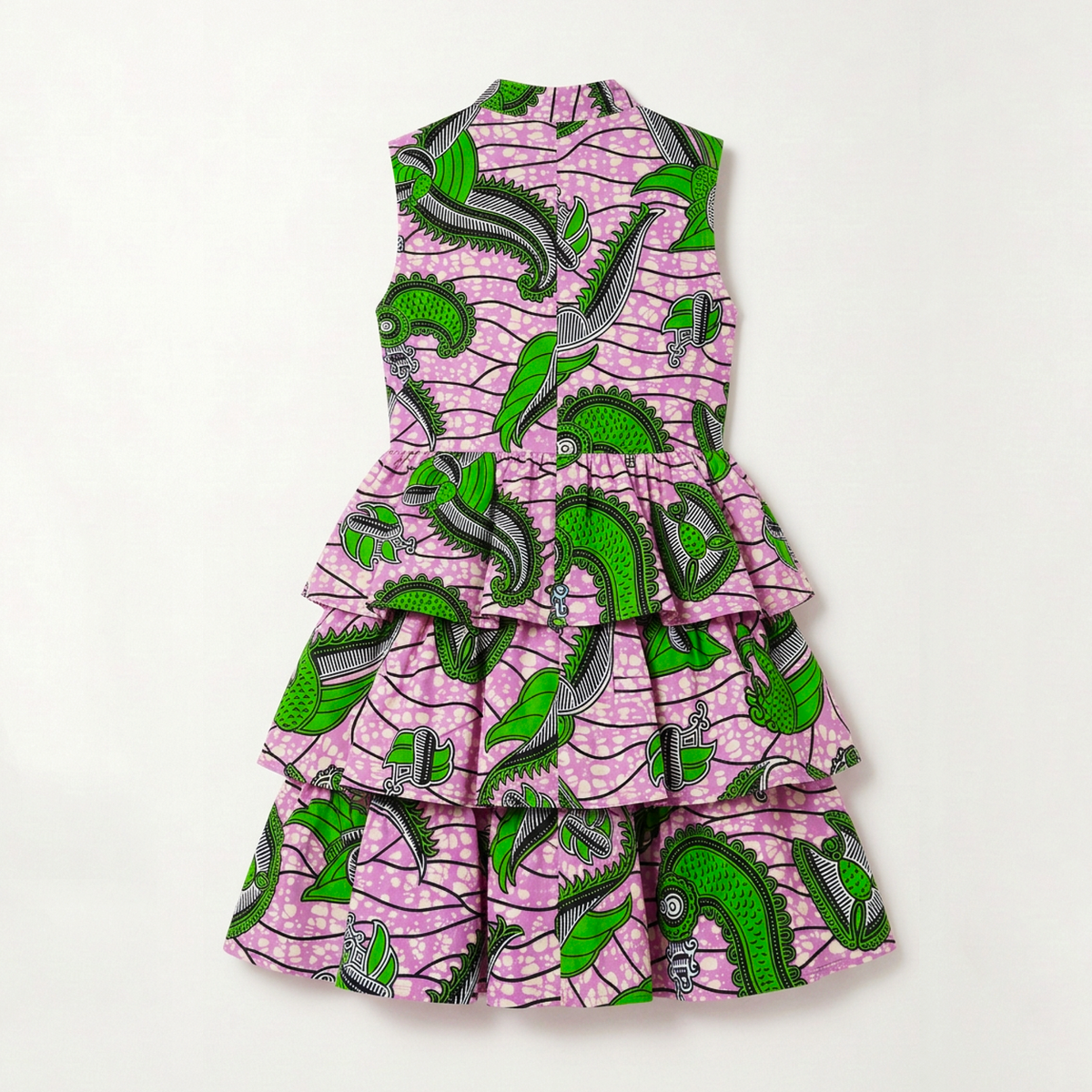 A sleeveless tiered dress featuring a vibrant green and black abstract pattern on a light pink background, laid flat against a clean white backdrop.