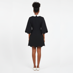 Person wearing a black dress with puffed sleeves on a white background