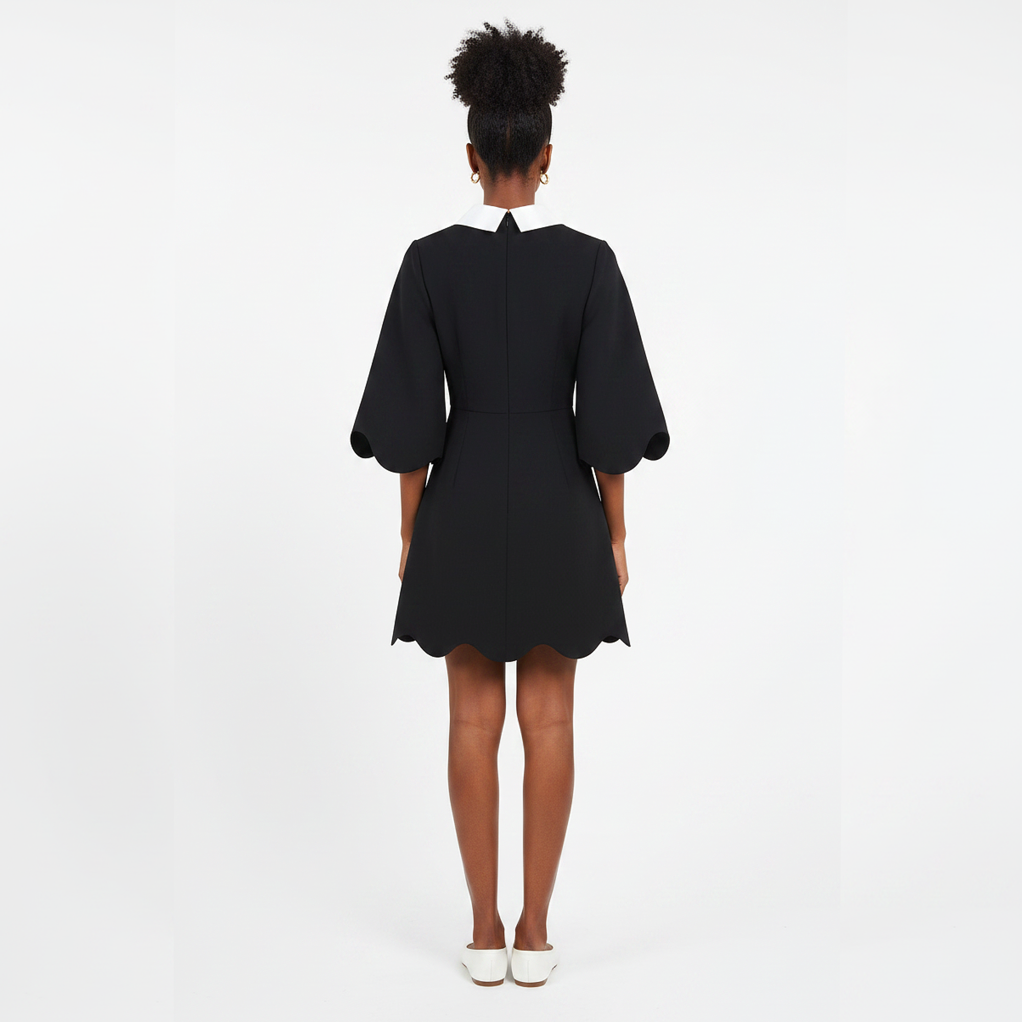 Person wearing a black dress with puffed sleeves on a white background