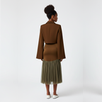 Woman wearing a brown jacket and skirt with a beige tulle hem on a white background