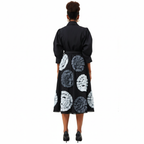 Black dress with white circular patterns worn by a person on a white background