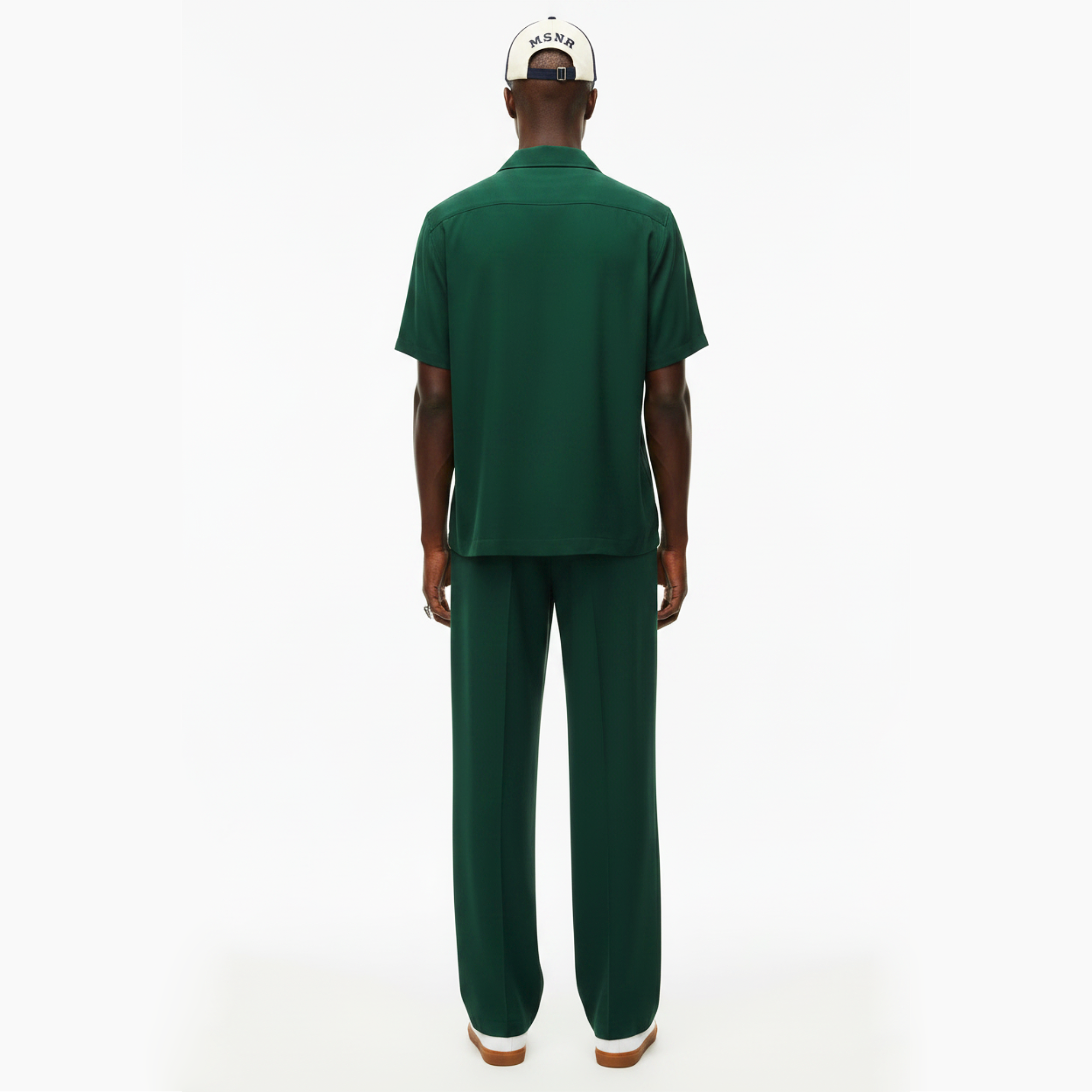 Person wearing a green outfit with a white cap on a white background