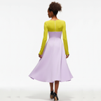 Woman wearing a yellow top and purple skirt on a white background