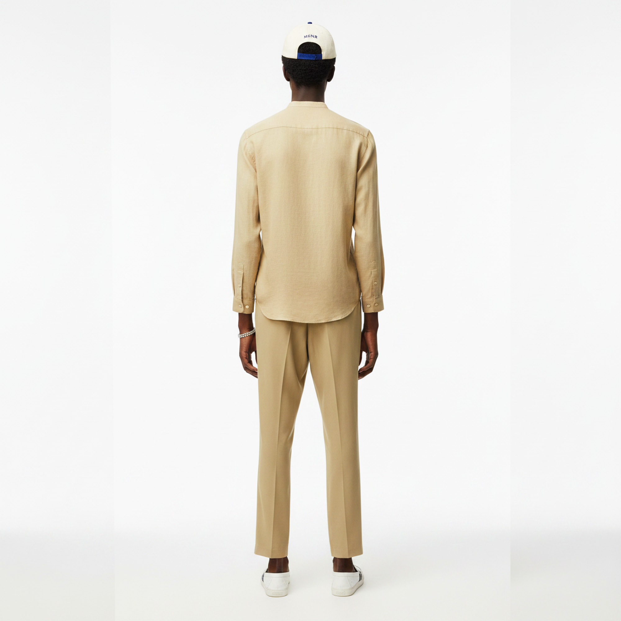 Person wearing a beige suit and white cap on a white background