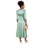 Woman wearing a green dress with floral designs against a white background