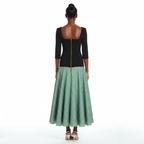 Woman wearing a black top and green checkered skirt on a white background