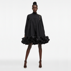 Black dress with ruffled skirt worn by a model on a white background