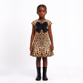 A young girl modeling a leopard print dress with a large black bow at the neckline, paired with black boots, against a plain white studio background.