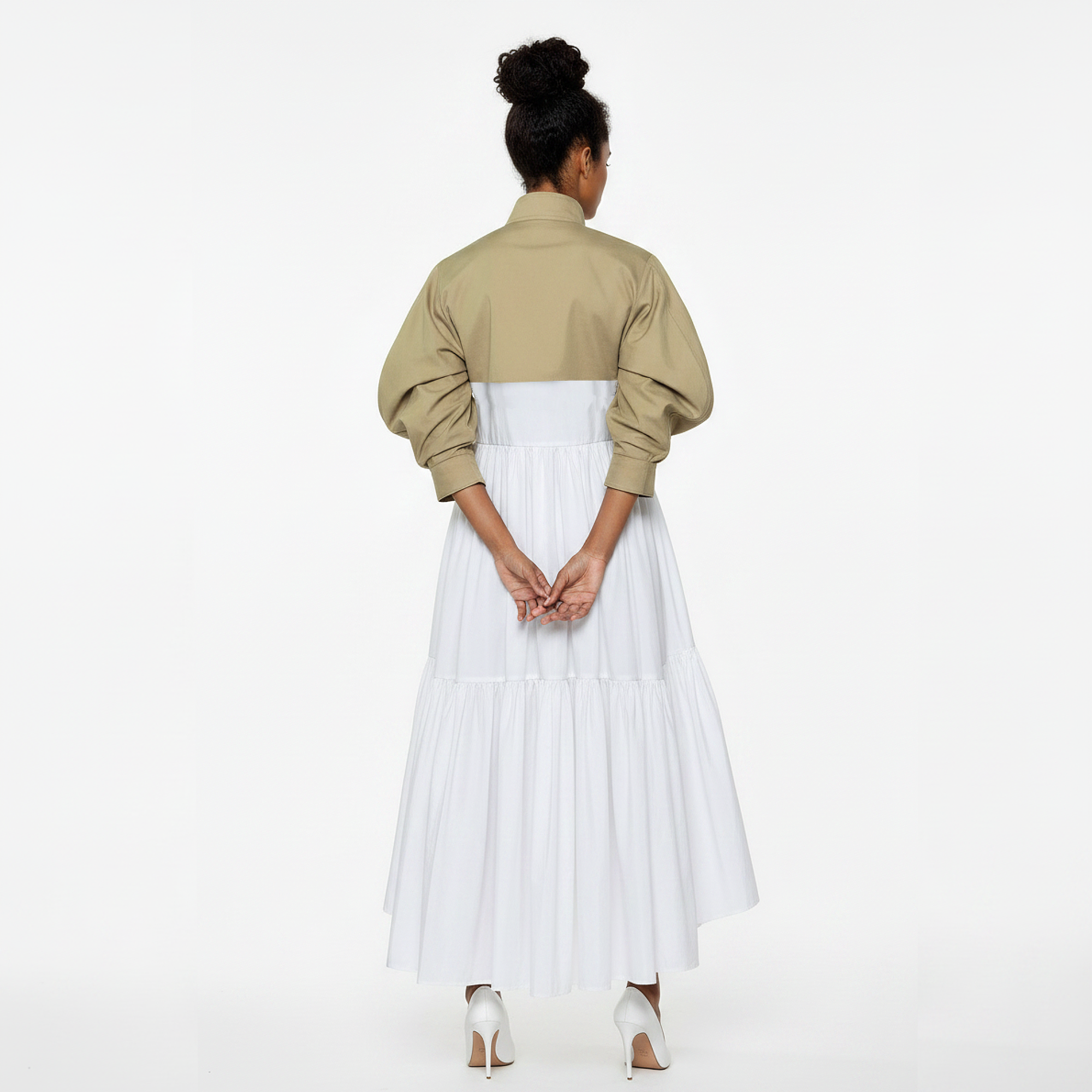 Woman wearing a beige jacket over a white dress on a white background