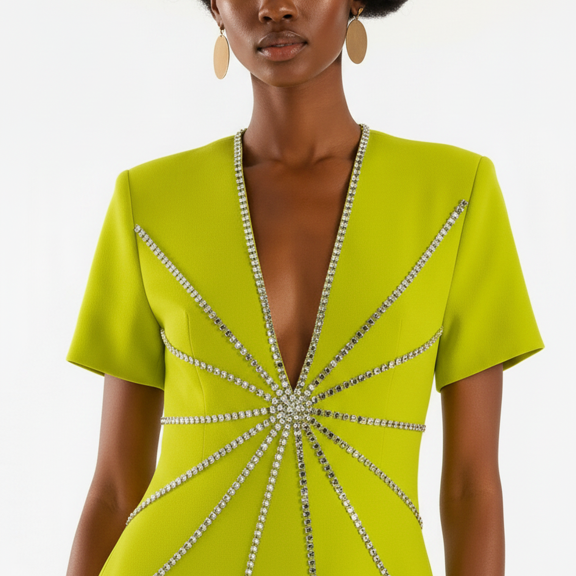 Woman wearing a lime green dress with a starburst pattern of embellishments on a white background