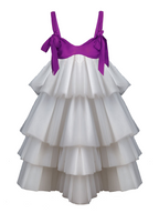 White tiered dress with a purple satin bow on a white background