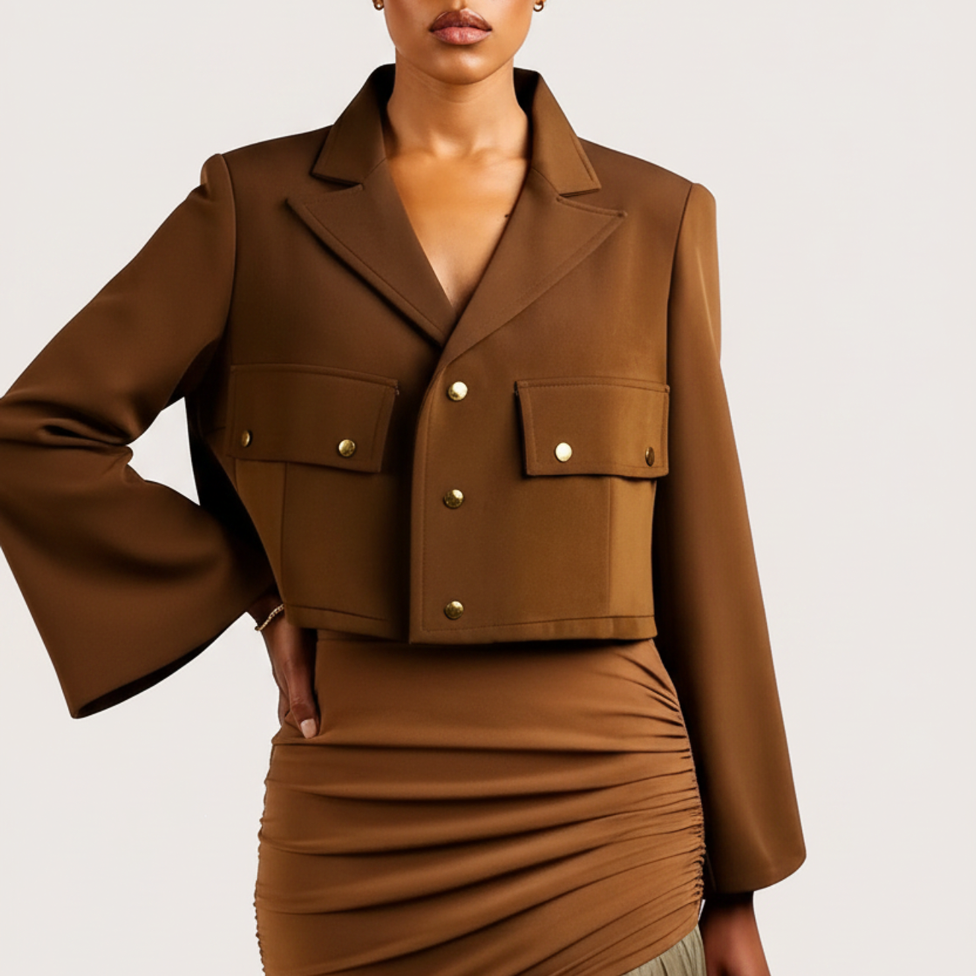 Woman wearing a brown jacket and skirt with a beige tulle hem on a white background