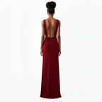 Woman wearing a burgundy evening gown with a backless design on a white background