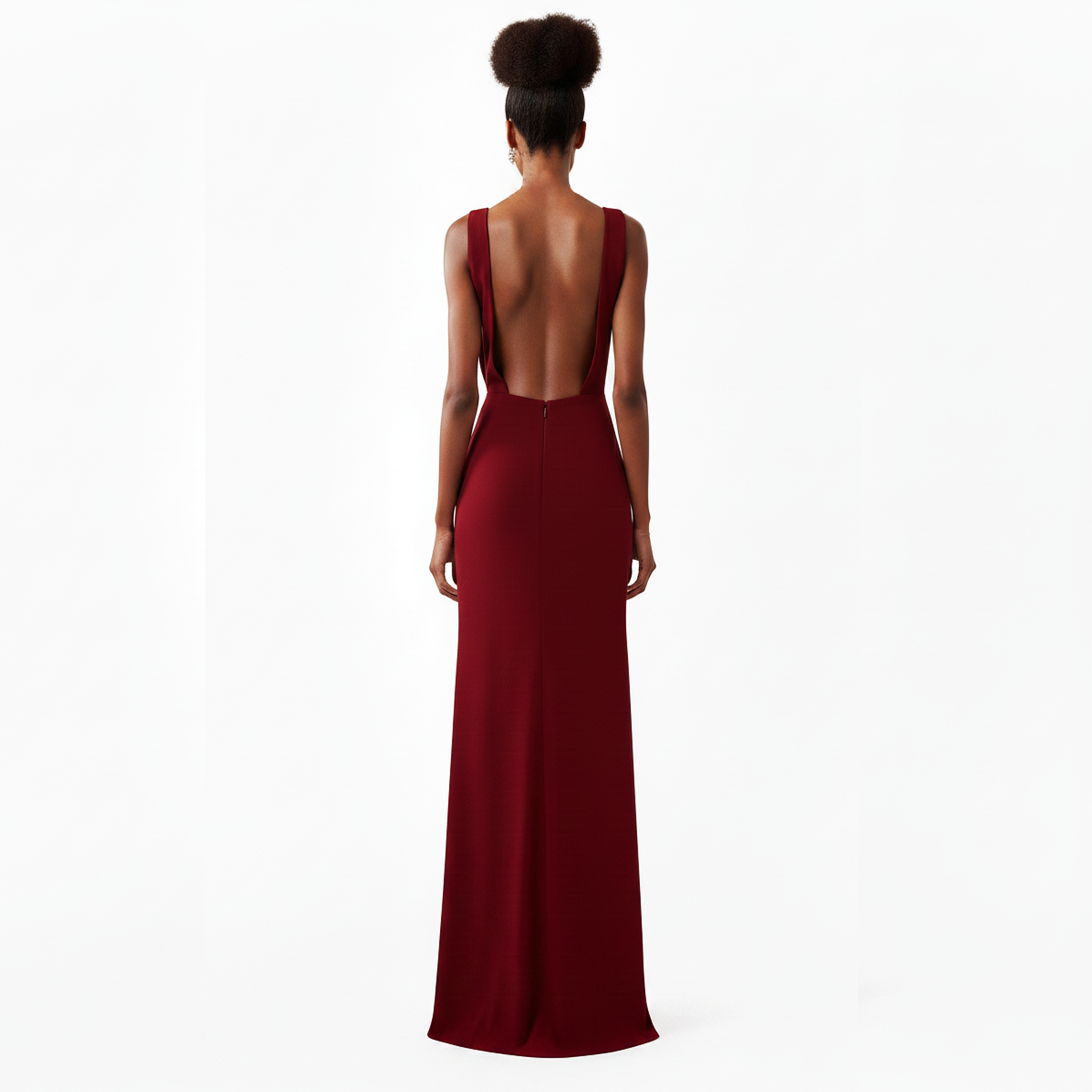 Woman wearing a burgundy evening gown with a backless design on a white background