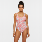 Woman wearing a pink floral one-piece swimsuit on a white background