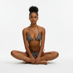 Woman wearing a black and white patterned bikini sitting on a white background