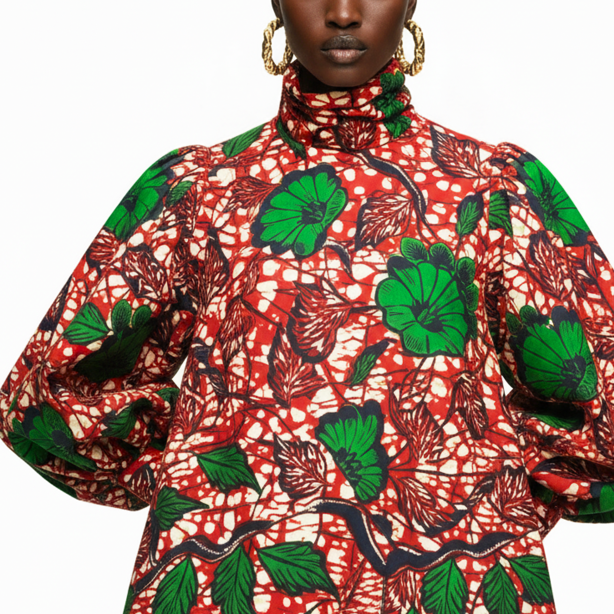 A close-up of a model wearing a high-neck, long-sleeve top with a vibrant red, green, and black African wax print pattern.
