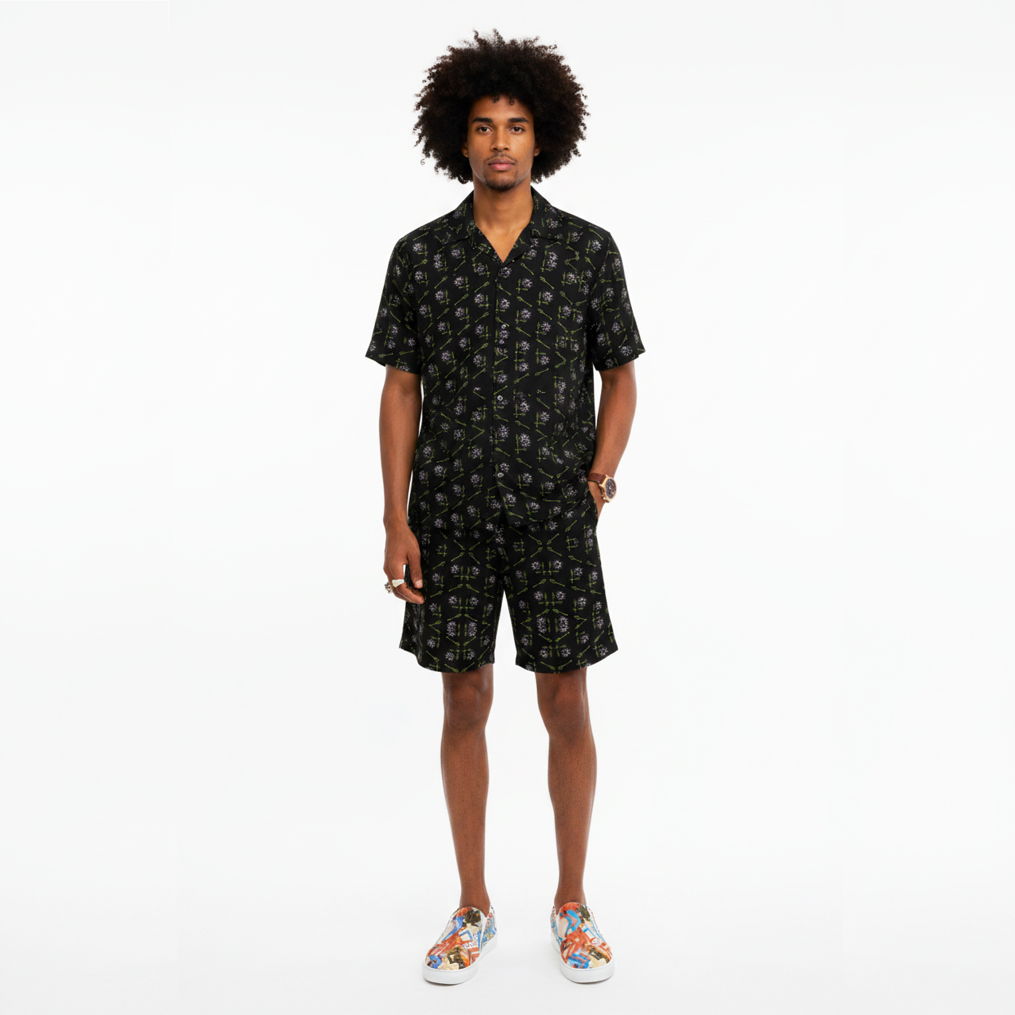 Man wearing a black patterned shirt and shorts set on a white background