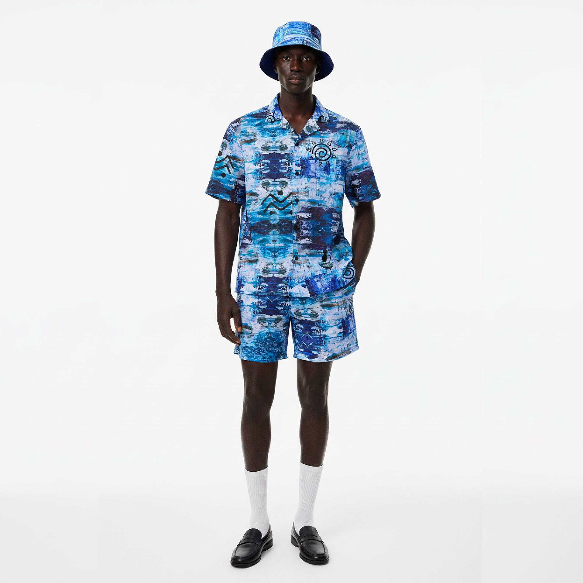 Person wearing a blue patterned outfit with a matching hat on a white background