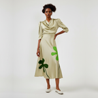 Woman wearing a beige dress with green clover patterns on a white background
