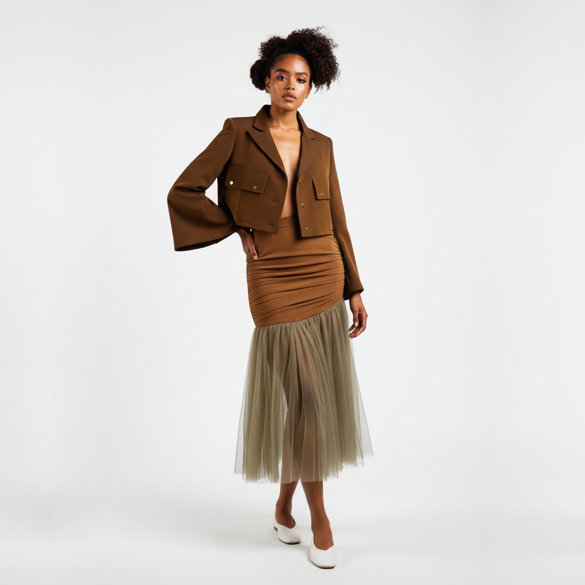 Woman wearing a brown jacket and skirt with a beige tulle hem on a white background