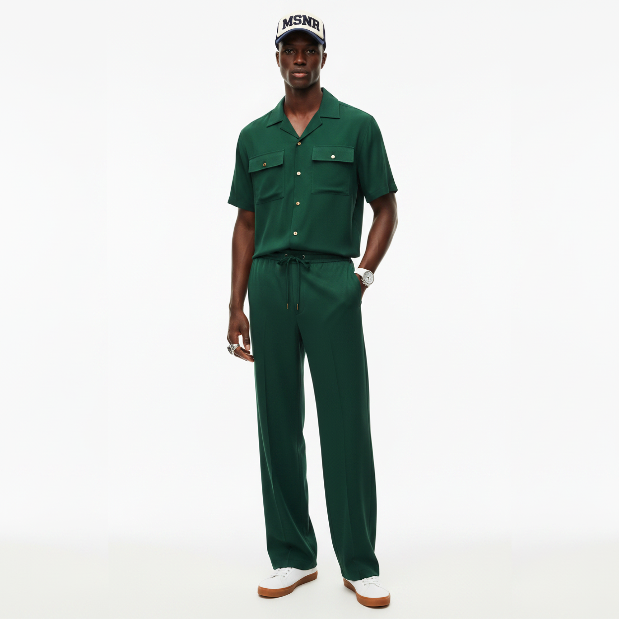 Man wearing a green jumpsuit and cap on a white background