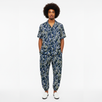 Man wearing a navy blue patterned jumpsuit on a white background