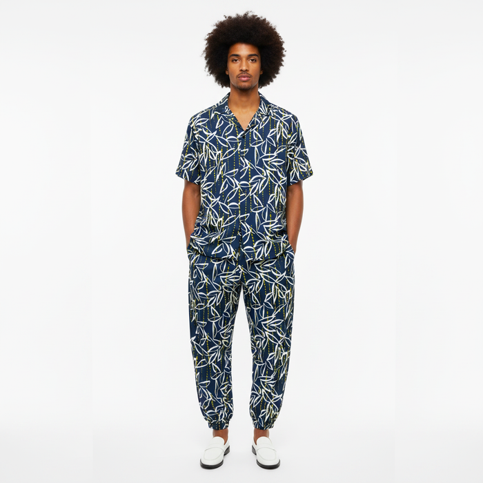 Man wearing a navy blue patterned jumpsuit on a white background
