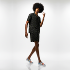 Person wearing a black patterned dress with colorful shoes on a white background